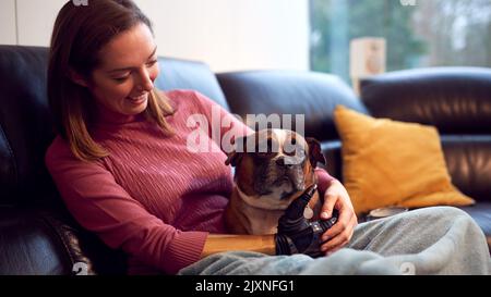 Femme avec bras prothétique et main à la maison avec chien d'animal de compagnie Banque D'Images