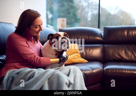 Femme avec bras prothétique et main à la maison avec chien d'animal de compagnie Banque D'Images