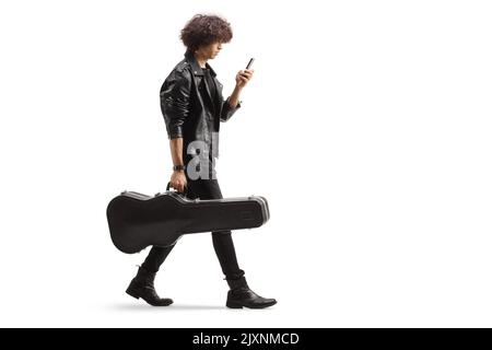 Prise de vue en profil d'un jeune musicien portant une sacoche de guitare et utilisant un smartphone isolé sur fond blanc Banque D'Images