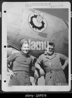 Deux membres de l'équipage de sol du 94th Fighter Squadron, le 1st Fighter Group, posent à côté de leur Lockheed P-38 Lightning dans un aérodrome quelque part en Italie. ['le Joker'] Banque D'Images