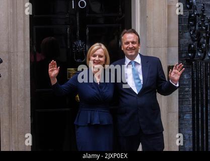 Le nouveau premier ministre, Liz Truss, se promène dans Downing Street avec son mari, Hugh O'Leary. Ils s'arrêtent et branle à la porte du numéro 10 avant son discours. Banque D'Images