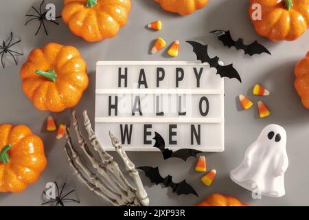 Tableau d'affichage Happy Halloween avec citrouille, chauve-souris et bonbons sur fond gris Banque D'Images