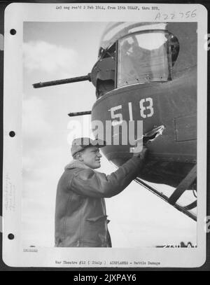 Sgt. Robert F. Hahn, Rochester, New York, canon à tourelle de nez sur un bombardier B-24 Liberator consolidé de 15th AAF, examine un trou fabriqué par une coquille de 20 mm d'un combattant allemand. La coque s'est avérée être un dud, et n'a pas explosé après avoir pénétré le Banque D'Images