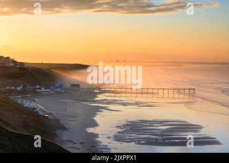 Saltburn Pier capturé peu après le lever du soleil de la plage. Banque D'Images