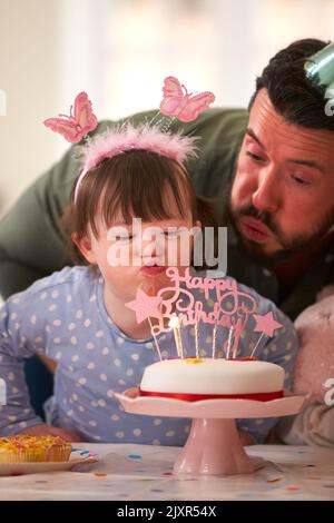 Père avec le syndrome de Down fille célébrant anniversaire avec la fête à la maison ensemble Banque D'Images