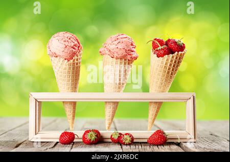 Glace à la fraise dans des cornets de gaufres et bol avec baies sur la table de jardin Banque D'Images