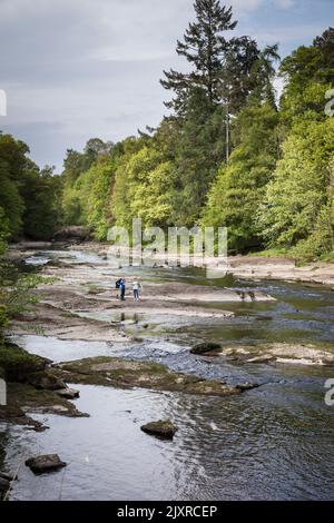 Les enfants jouent sur les rochers exposés de la rivière rapide Ericht, Blairgowrie, Écosse. Banque D'Images