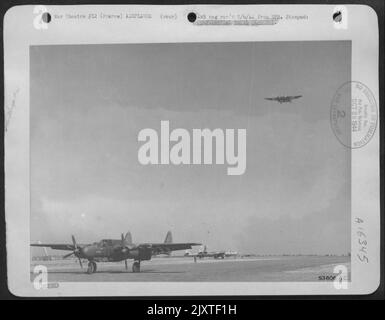 L'un des chasseurs de nuit Northrup P-61 Black Widow récemment annoncé roule le long de la piste tandis qu'un autre flis au-dessus d'une base aérienne de défense 9th AF quelque part en France. Banque D'Images