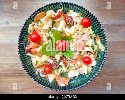 Salade de morceaux de chicorée avec des pommes, des tomates cerises et des carottes en tranches, garni de baume de citron et de tomates. Vue de dessus, plaque de verre vert foncé avec Banque D'Images