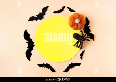 Composition de chauves-souris noires, araignée tricotée, citrouille orange tricotée avec un endroit rond jaune pour le texte. Concept Halloween. Banque D'Images
