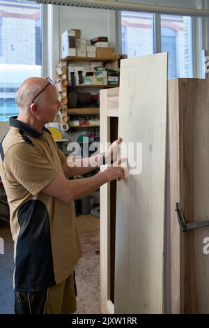 Menuisier Vérification de son esquisse sur la planche en bois à usiner. Russikon, Oberland de Zurich, Suisse Banque D'Images