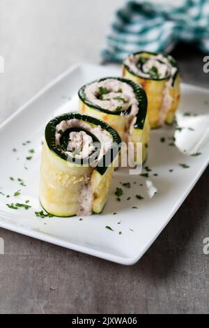 Rouleaux de courgettes grillées farcis au fromage à la crème et au thon sur une table en bois Banque D'Images