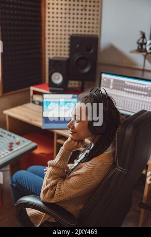 Ingénieur du son assis à table avec tableau de mixage de l'équipement électronique d'enregistrement sonore dans un studio d'enregistrement sonore professionnel Banque D'Images