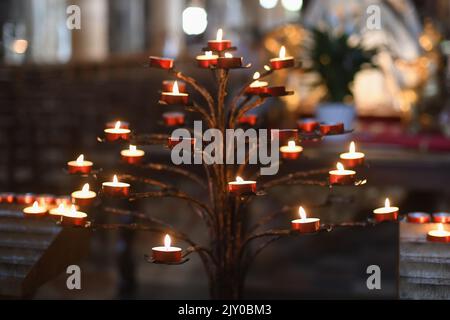 Beaucoup de bougies dans l'église catholique sombre Banque D'Images