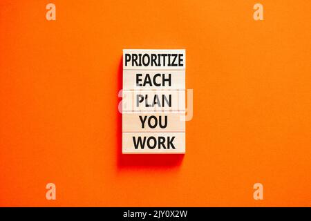 Donnez la priorité à chaque symbole de plan que vous travaillez. Les mots de concept donnent la priorité à chaque plan que vous travaillez sur des blocs de bois sur un magnifique fond orange. Priorité de l'entreprise Banque D'Images