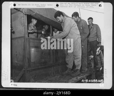 Les hommes du 612Th e Escadron de génie, 364th Groupe de service, font monter la rampe de type Stile sur le côté du chariot Chuck pour prendre leur repas de midi; PFC. Milton Rosen, de Brooklyn, New York, est en tête de file. Le menu comprenait du Spam frit, des pois verts, de la viande et du veau Banque D'Images