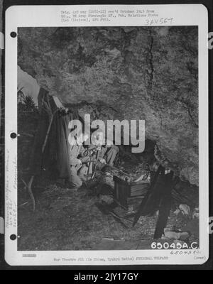 Un incendie sous une roche surpenchée assèche des couvertures « GI » de sodden le matin après Une pluie tentante sur les habitants des tentes de Pup du Groupe de service 364th de l'escadron 612Th du Génie aérien. Les hommes sont, de gauche à droite: Sgt. Gordon J. Essler, 18 Railroad Ave., Beverly Mas Banque D'Images