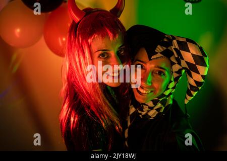 Amis en costume souriant dans une fête d'halloween en intérieur Banque D'Images