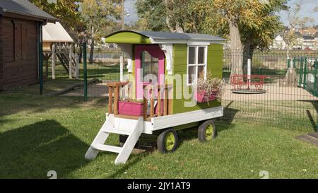 Petite caravane de voyageurs en bois vert et pink debout sur une pelouse Banque D'Images