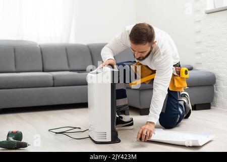 Jeune homme changer - réparer un purificateur d'air sale filtre HEPA après une longue utilisation. Un réparateur remplace et installe le filtre du purificateur d'air Banque D'Images