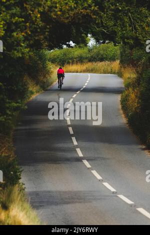 Seul cycliste sur la route de la campagne à Devon, Royaume-Uni Banque D'Images