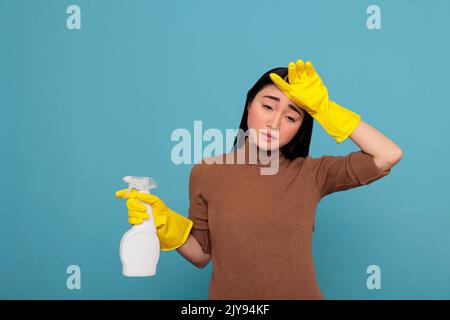 Fatiguée frustrée et malheureuse femme de ménage asiatique de tout le nettoyage portant des gants en caoutchouc jaune. Épuisé stressé femme de ménage surtravaillée et corvées avec un état d'esprit négatif Banque D'Images