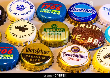 Une variété de capsules internationales de bouteille de bière disposées en rangées sur une table en bois. Banque D'Images