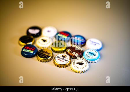 Une variété de capsules internationales de bouteille de bière disposées en rangées sur une table en bois. Banque D'Images