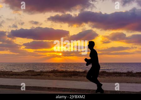 Haïfa, Israël - 05 septembre 2022: Scène de coucher de soleil sur la côte de la mer Méditerranée, avec silhouette de jogger. Haïfa, nord d'Israël Banque D'Images