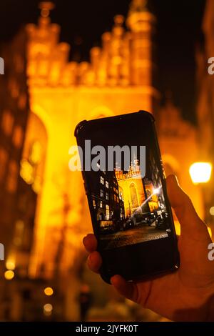 Tourisme prendre des photos sur téléphone portable de Cityscape de Gdansk avec la basilique Sainte-Marie et l'hôtel de ville la nuit, Pologne. Belle architecture de la rue Mariacka. Concept de médias sociaux église Sainte Marie dans le centre de la vieille ville. Célèbre rue européenne à Gdansk. Visitez Gdansk. Destination du voyage. Attraction touristique Banque D'Images