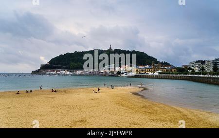 Paysage de la plage de la Concha dans la ville de Saint-Sébastien, par une journée ensoleillée avec les gens appréciant la plage et le Mont Urgull en arrière-plan. Banque D'Images