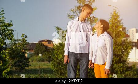 La jeune femme et l'homme handicapés tiennent les mains souriantes au coucher du soleil Banque D'Images