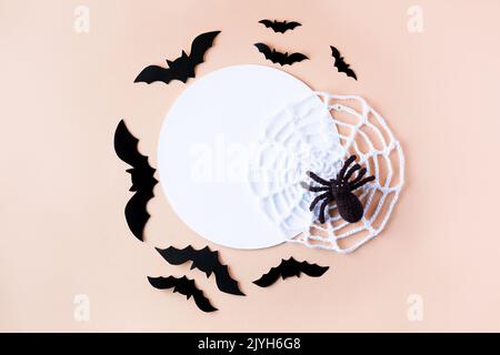 Composition de chauves-souris noires et d'une araignée tricotée avec une toile blanche avec un endroit blanc rond pour le texte. Concept Halloween. Banque D'Images