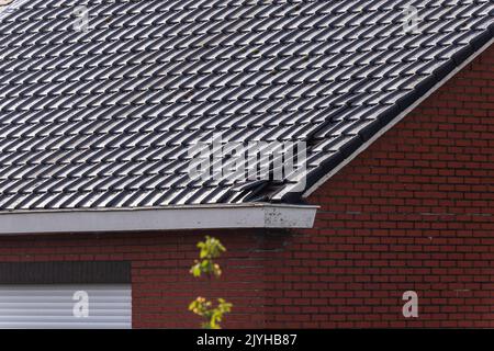 Un portrait d'un toit en carreaux noirs détruit d'une maison. Le bâtiment a été endommagé par une grosse tempête avec des vitesses de vent élevées sur l'échelle de beaufort en Belgique d Banque D'Images