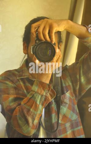 Gros plan d'un photographe de sexe masculin prenant photo de lui-même devant le miroir dans la salle Banque D'Images