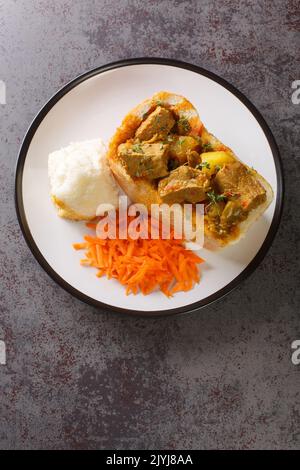 Pain de vache à lapin sud-africain farci de curry d'agneau avec légumes en gros plan sur une assiette sur la table. Vue verticale du dessus Banque D'Images