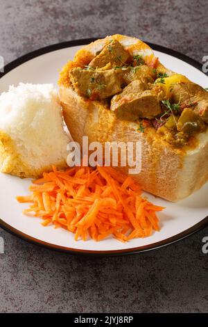 Pain de lapin sud-africain farci de curry d'agneau avec légumes en gros plan sur une assiette sur la table. Vertical Banque D'Images