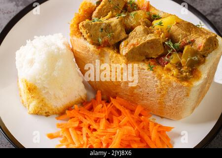 Gros plan de lapin d'agneau chow la populaire, cuisine indienne rapide qui est originaire d'Afrique du Sud, avec salade de carottes sur l'assiette sur la table. Horizontale Banque D'Images