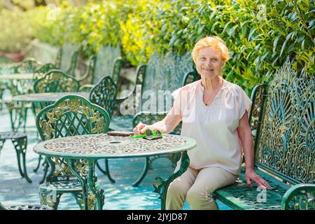 Femme mature attrayante voyageur assis seul sur la terrasse du café-restaurant Banque D'Images