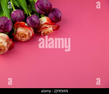 Bouquet de roses et tulipes sur fond rose. Mise en page d'une carte de vœux. Concept de ressort. Copier l'espace. Vue de dessus des fleurs. Fleur de tulipe. Banque D'Images