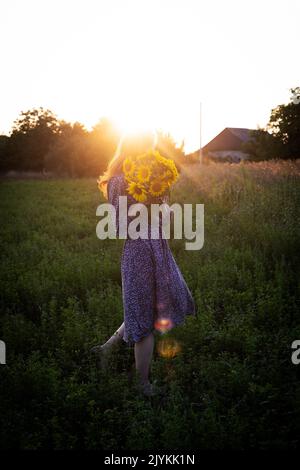 fille tenant un énorme bouquet de tournesols dans leurs mains dans la lumière du coucher du soleil Banque D'Images