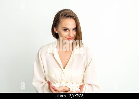 Portrait d'une jeune femme caucasienne tenant des cubes de sucre en tas debout et regardant l'appareil photo sur un fond blanc Banque D'Images