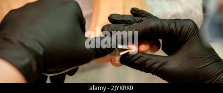 Pédicure professionnelle. Pédicure maître portant des gants en latex coupe les ongles du pied féminin dans le salon de beauté, gros plan Banque D'Images