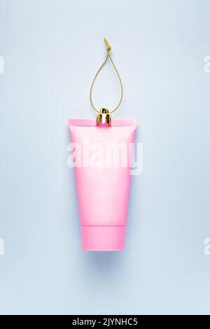 Fond de Noël festif avec une décoration de Noël et un tube de crème en plastique rose. Le concept de salutations, les célébrations du nouvel an Banque D'Images
