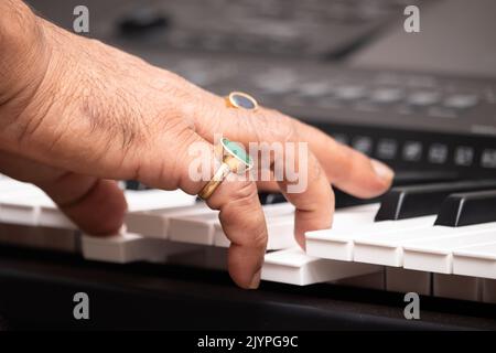 Mains de l'homme portant la Panna naturelle d'Emeraude et le bleu saphir Neelam Gemstone jouant des notes sur le piano ou le clavier. Formation musicale ou coaching, Live Mu Banque D'Images