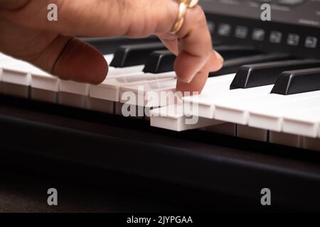 Mains de l'homme portant la Panna naturelle d'Emeraude et le bleu saphir Neelam Gemstone jouant des notes sur le piano ou le clavier. Formation musicale ou coaching, Live Mu Banque D'Images