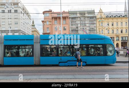 Vue latérale d'un tramway bleu articulé avec des passagers sur la place Ban Jelacic à Zagreb, Croatie, Europe Banque D'Images