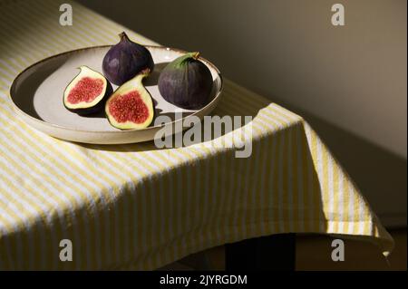 Figues fruits placés sur une petite assiette sur une table avec une nappe et le soleil Banque D'Images