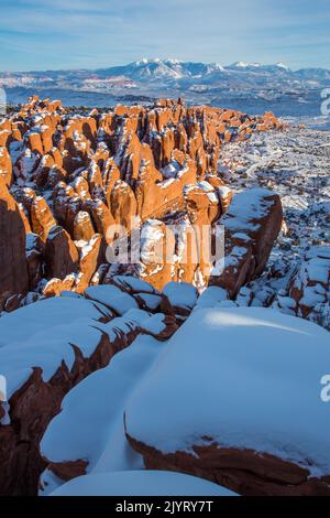 Neige sur les nageoires en grès Entranda de Fiery Furnace avec les montagnes enneigées de la Sal derrière. Parc national Arches, Moab, Utah. Banque D'Images