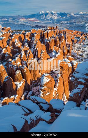 Neige sur les nageoires en grès Entranda de Fiery Furnace avec les montagnes enneigées de la Sal derrière. Parc national Arches, Moab, Utah. Banque D'Images